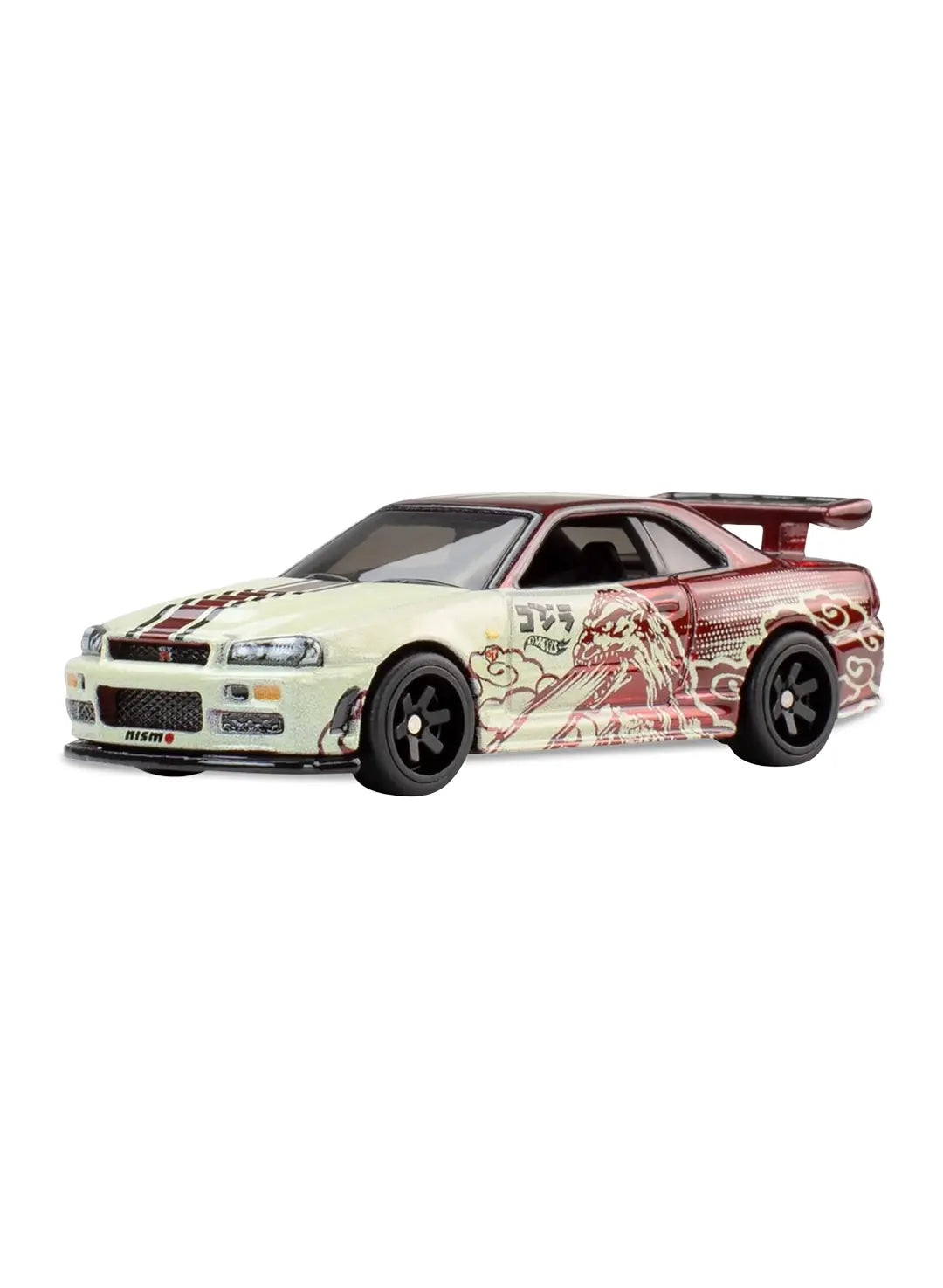 Close-up view of the white Hot Wheels Godzilla Nissan Skyline GT-R (BNR34) showing side red monster scale decals, Japanese text graphics, a rear wing, and black 6-spoke Real Riders wheels.