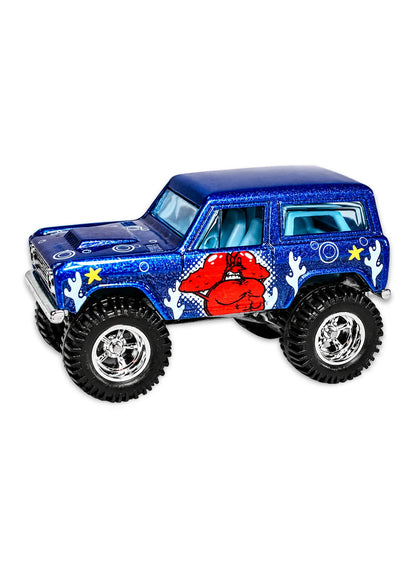 Close-up view of the metalflake blue Hot Wheels Larry the Lobster '67 Ford Bronco showing side graphics and off-road Real Riders wheels.