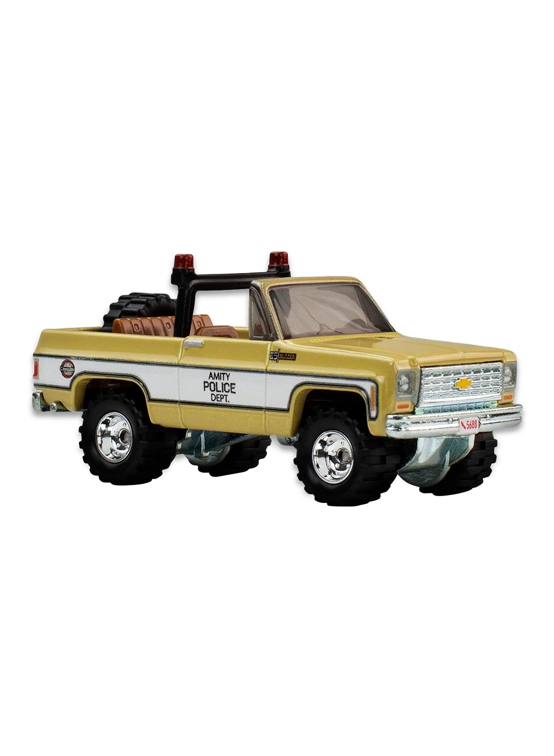 Close-up view of the tan and white Hot Wheels JAWS Amity Police Dept '75 Chevy Blazer Custom truck showing an open cargo bed, a small roof light, and chrome mag-style Real Riders wheels.