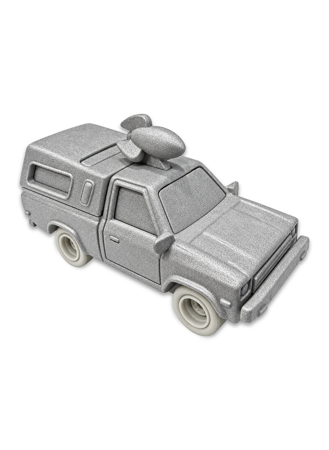Close-up view of the stone-textured matte grey Hot Wheels The Good Dinosaur Pizza Planet Truck showing a sculpted fossilized rocket ship roof topper, rugged prehistoric truck panels, and matching grey stone Real Riders wheels.